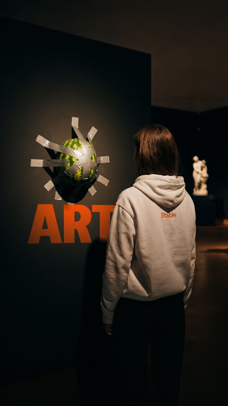 Visitor in a Stable hoodie looking at a piece in an art gallery